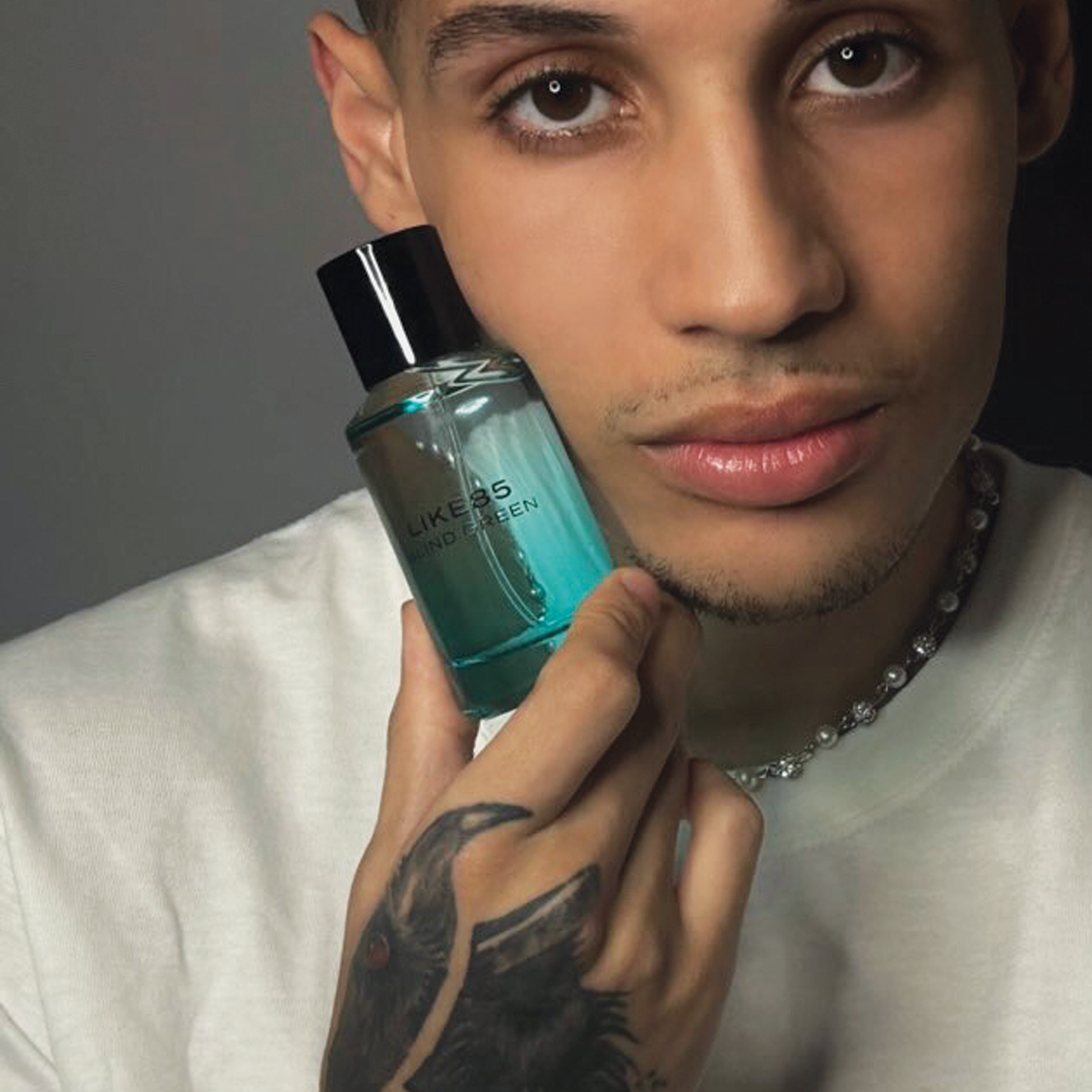 Latino male model holding Blind Green Fragrance bottle with tattoo